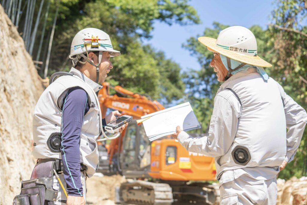 工事現場で笑顔で話し合う2人の作業員